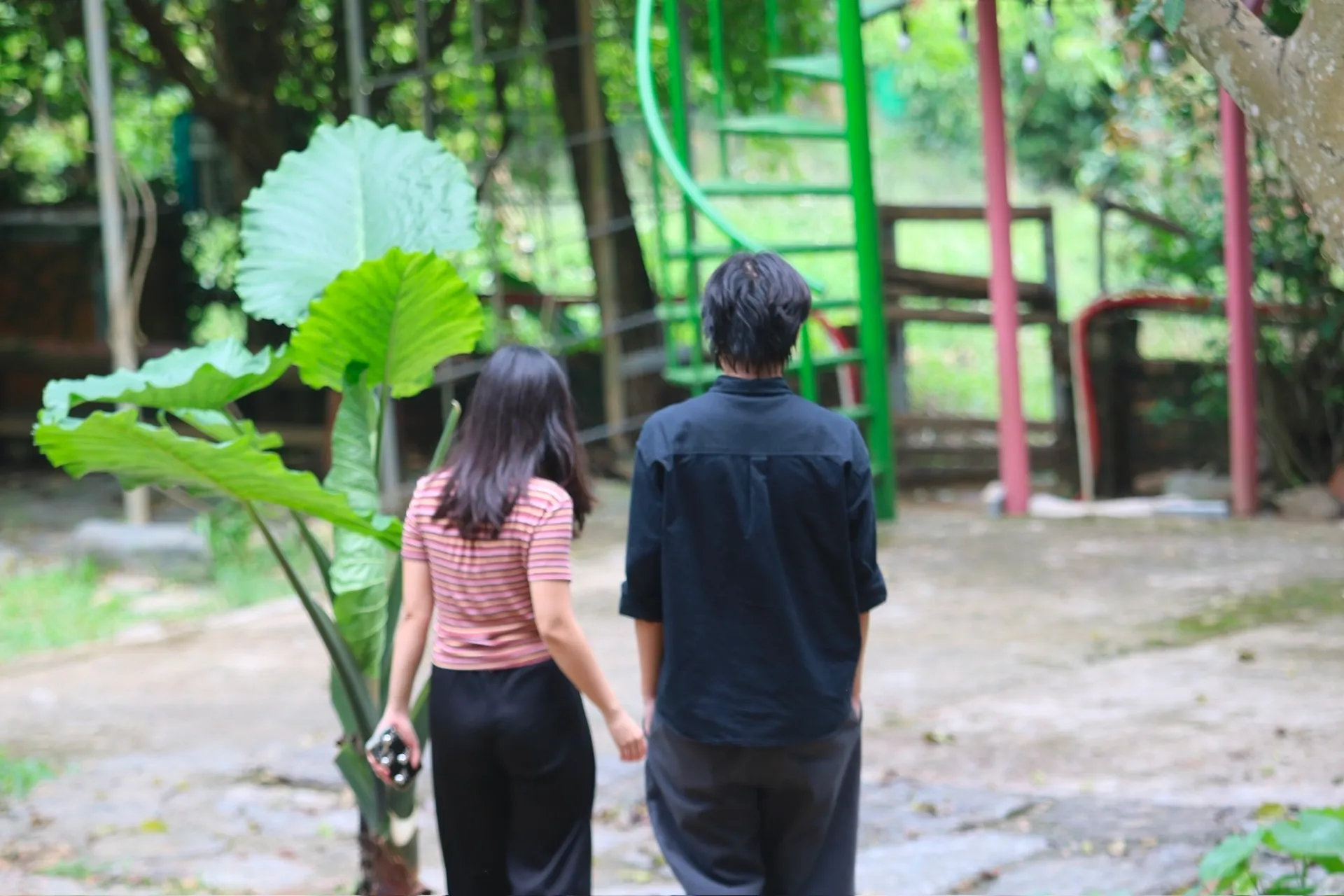 Hai người đi bộ cạnh nhau trên lối đi trong khu vườn ở Làng Hạnh Phúc 5M